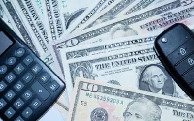 US dollars, calculator, and car keys representing finance and investment tools.