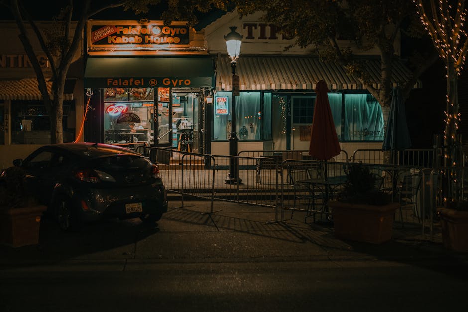 Illuminated city street scene of a cozy falafel and gyro shop at night, inviting urban ambiance.