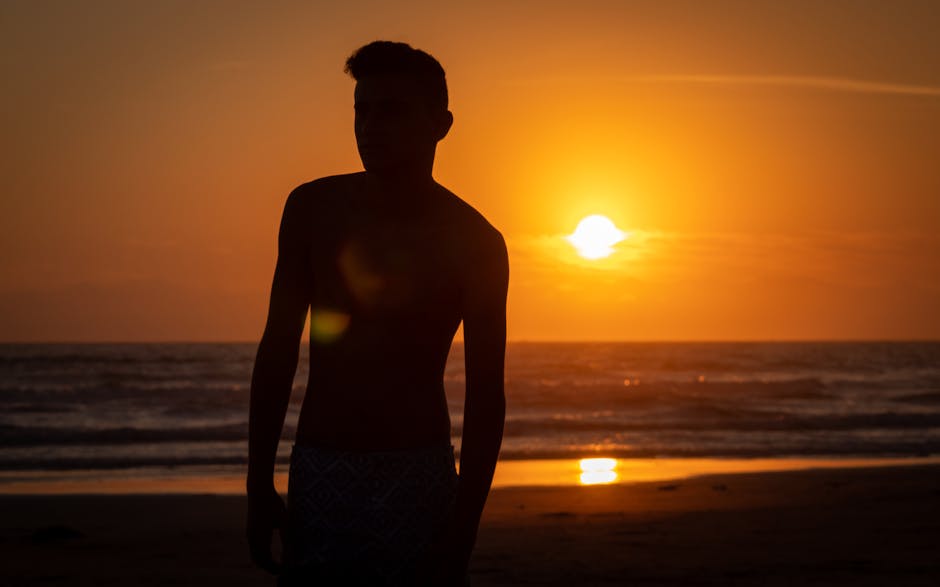Silhouette of a man on a beach at sunset, capturing a dramatic and serene seascape.