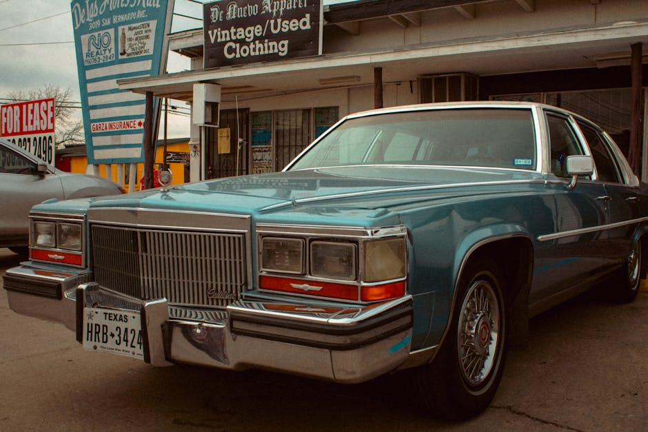 A vintage Cadillac parked outside a storefront under a cloudy sky, evoking nostalgia and classic urban charm.