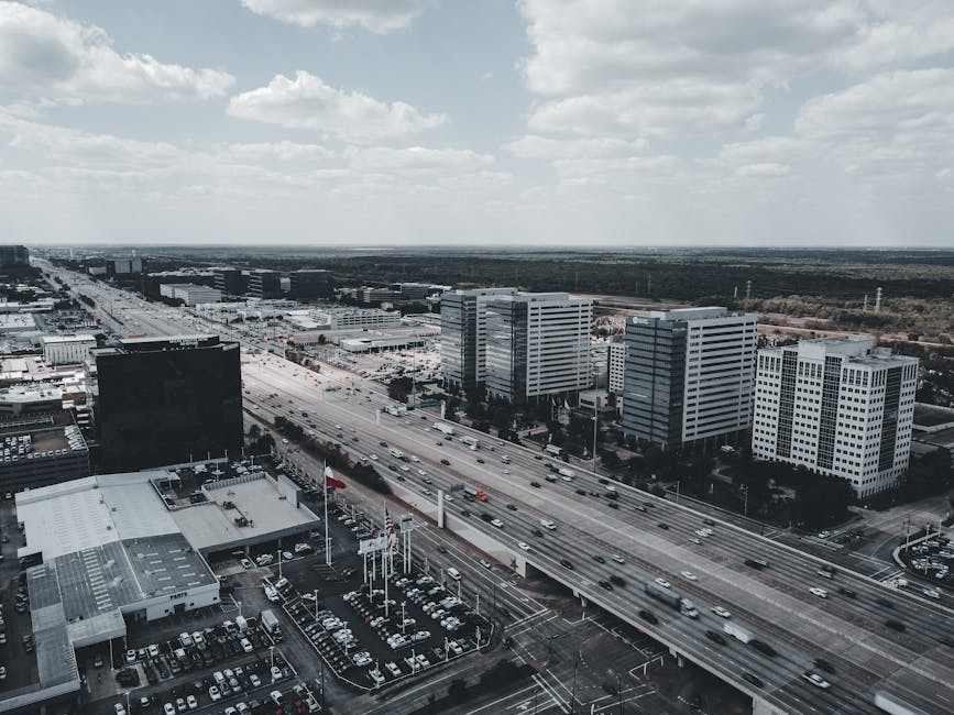An aerial shot capturing a bustling highway intersecting a modern urban cityscape with tall buildings.