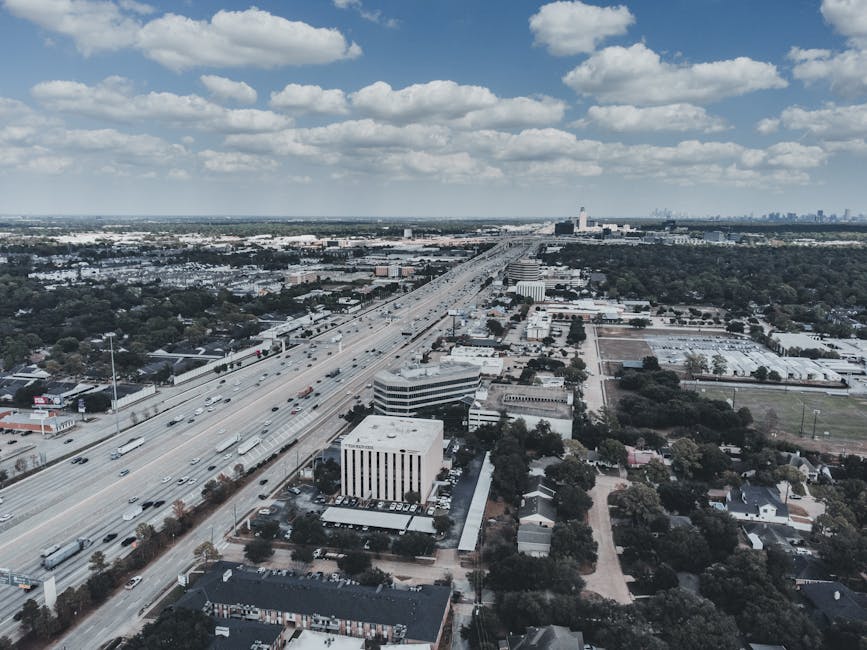 Expansive aerial cityscape with highway, showcasing urban development and open sky.